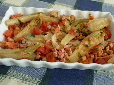 Insalata belga in padella con prosciutto pomodori e profumo di basilico