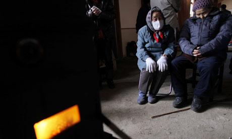 An couple sit near a stove in gymnasium being used to house those displaced in town of Otsuchi