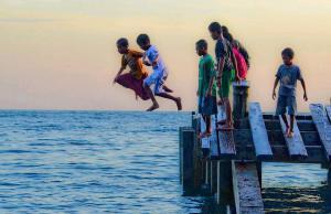 Indonesia Bambini saltano in mare vicino alla spiaggia di Susupu