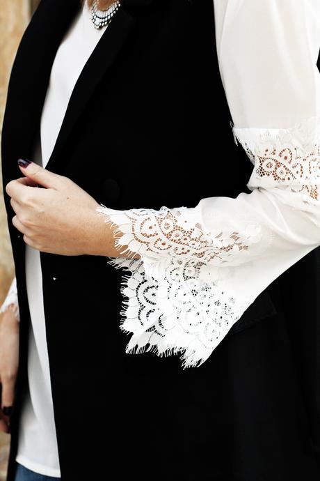 Top bianco con maniche in pizzo, gilet nero e borsa rossa