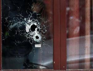 epa05024526 A man looks outside the Carillon cafe with bullets holes on the glasses, in Paris, France, 14 November 2015. At least 120 people have been killed in a series of attacks in Paris on 13 November, according to French officials. Eight assailants were killed, seven when they detonated their explosive belts, and one when he was shot by officers, police said. French President Francois Hollande says that the attacks in Paris were an 'act of war' carried out by the Islamic State extremist group.  EPA/YOAN VALAT