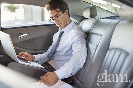 Businessman using laptop in back seat of car