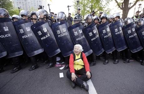 Una donna partecipa a una manifestazione contro il governo davanti a un cordone di polizia a Seul, in Corea del Sud (AP Photo/Lee Jin-man)