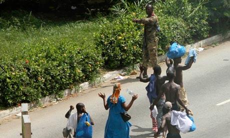 Civilians pass pro-Gbagbo soldier in Abidjan