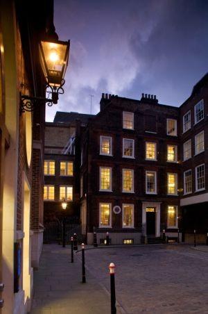 A photo of a historic house in a city, lit up at night