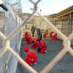 A file photo shows detainees sitting in a holding area watched by military police at Camp X-Ray inside ...