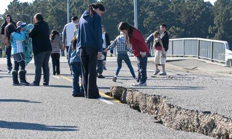 People inspect the earthquake-damaged roadway on the South  Brighton Bridge approach